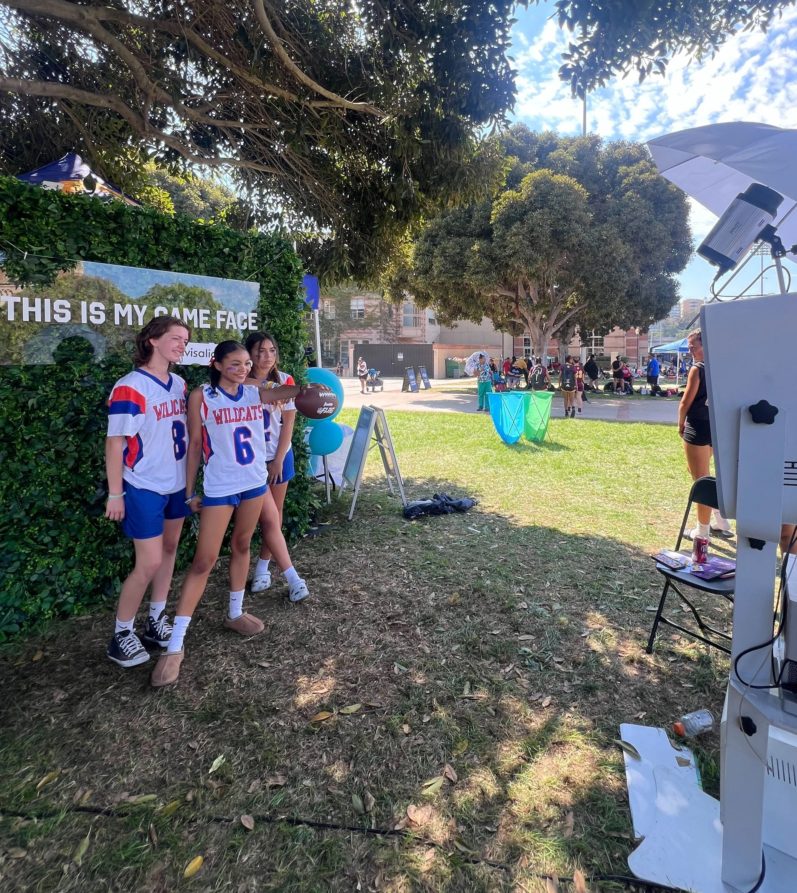 Outdoor sports team using premium photo booth with flower wall backdrop